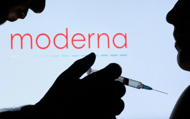 Pessoas posam com uma seringa com agulha em frente ao logotipo da Moderna exibido nesta ilustração tirada em 11 de dezembro de 2021.